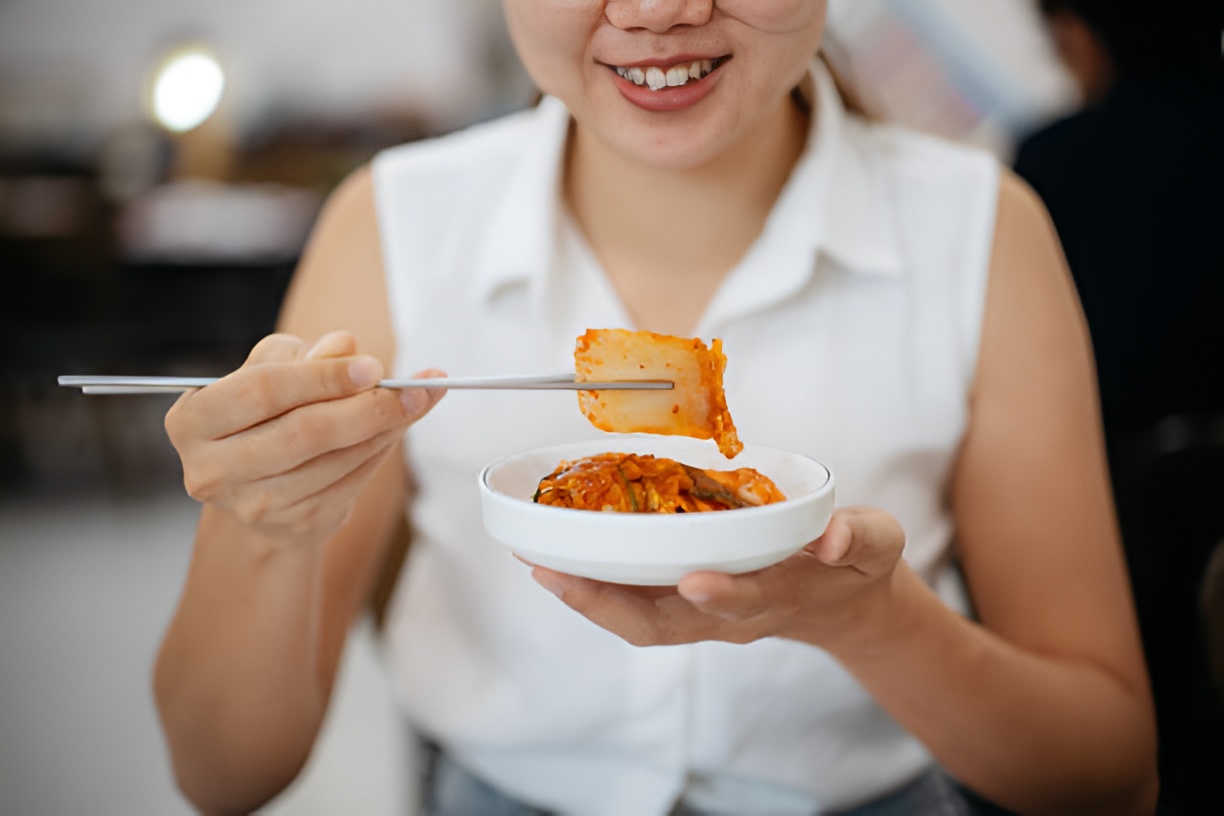 woman eating kimchi with metal chopsticks